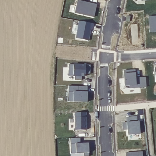 Later aerial view showing houses and paved streets beside the field